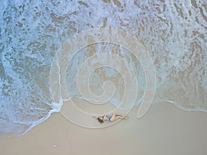overhead view of woman in blue swimsuit at sea beach
