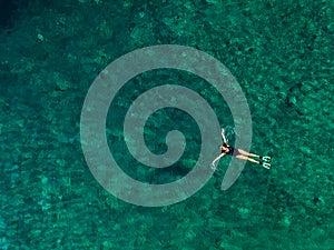 overhead view of woman floating on back in clear sea water