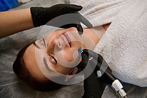 Overhead view of a woman getting facial hydro microdermabrasion peeling treatment at cosmetic beauty spa clinic. Hydra vacuum