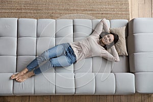 Overhead view woman put hands behind head relaxing on sofa