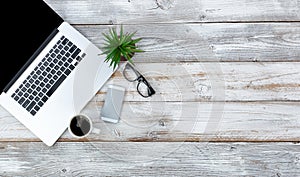 Top view of working desktop and smart phone, coffee, reading glasses and baby plant with plenty of copy space