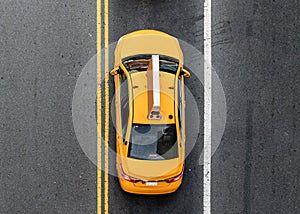 Overhead view of yellow New York City taxi driving between the lines on the road