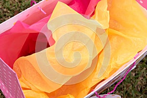 Overhead view of yellow and pink tissue paper in gift bag