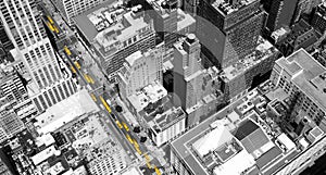 Overhead view of yellow taxis driving through the black and white buildings of Midtown Manhattan in New York City