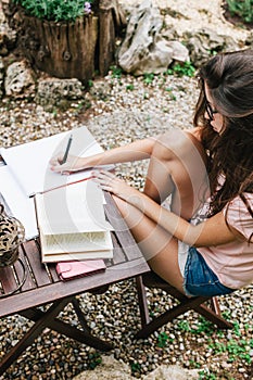 Overhead view of young beautiful female sitting outside and studying hard.