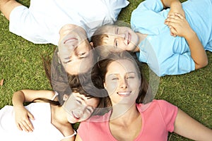 Overhead View Of Young Family Lying On Grass In Park