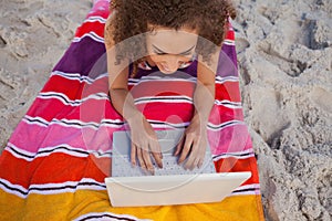 Overhead view of a young woman using her laptop on her beach towel