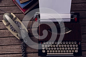 Vintage typewriter and telephone on wooden table