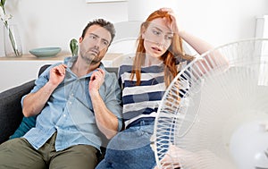 Overheated couple sitting on couch and feeling unwell suffering from heating at home