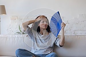 Overheated Hispanic woman wave fan, cooling herself at hot day