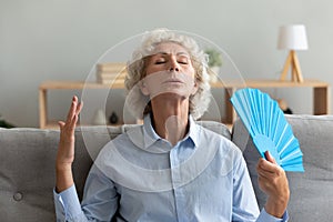 Overheated senior woman feel hot using hand waver