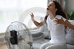 Overheated woman enjoying fresh air, cooling herself by electric fan