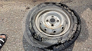 An overinflated car tyre fallen on the road after its tube burst in the street.