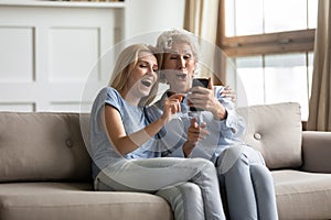 Overjoyed adult daughter and senior mom relax together