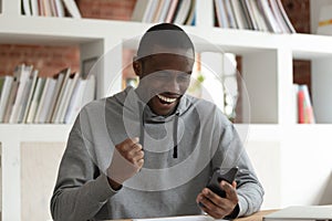 Overjoyed african American guy excited with cellphone message