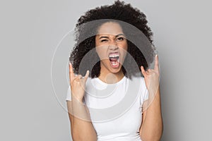 Overjoyed african american young woman showing hard rock horns gesture.