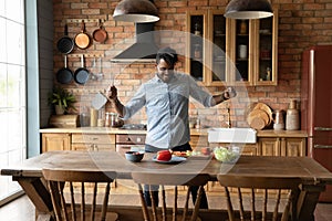 Overjoyed afro american guy dance by kitchen table preparing meal