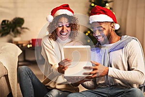 Overjoyed afro couple open xmas box and looking inside