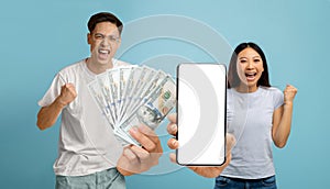 Overjoyed asian couple holding a lot of cash and smartphone