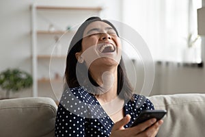 Overjoyed Asian girl laugh watching video on smartphone