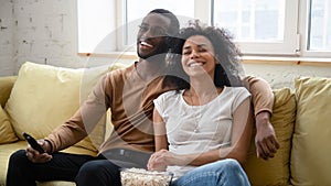 Overjoyed biracial couple have fun watching TV together
