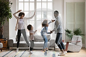 Overjoyed biracial family with kids have fun dancing photo