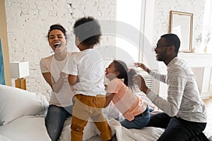 Overjoyed biracial family with kids playing together in bedroom