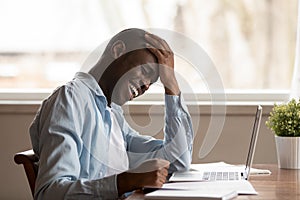 Overjoyed biracial man work at laptop laughing at joke