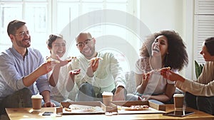 Overjoyed cheerful diverse friends gather together eating pizza enjoy conversation