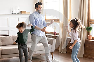 Overjoyed dad have fun dancing with little kids at home