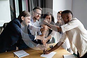 Overjoyed multiethnic businesspeople stack fists engaged in teambuilding photo
