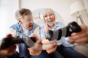 Overjoyed elder couple playing video games at home