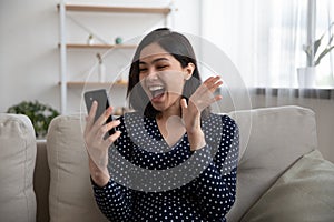 Overjoyed emotional happy millennial asian woman celebrating getting win notification.