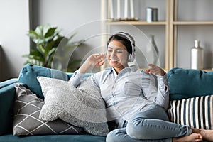 Overjoyed ethnic girl in headphones listen to music