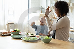 Overjoyed ethnic mom and Caucasian daughter cook at home