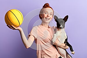Overjoyed excited ginger girl teaching her dog to play with a ball
