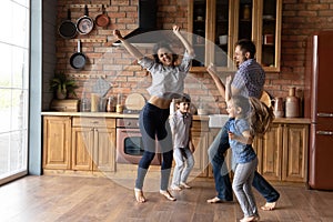 Overjoyed family dancing at kitchen celebrating moving to new home