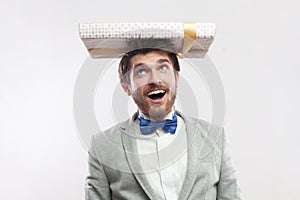 Overjoyed funny bearded man standing with present box on head, expressing happiness.