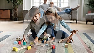 Overjoyed funny little children siblings playing toys on floor carpet.