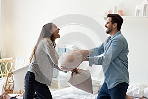 Overjoyed funny young married spouse fighting with pillows.