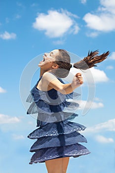 Overjoyed girl in blue dress spin summer day