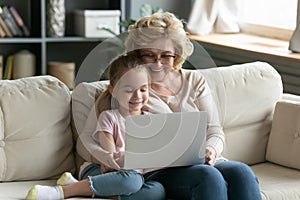 Overjoyed grandmother using laptop with small granddaughter photo