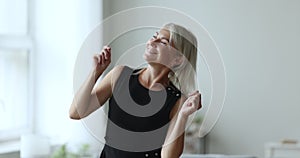 Overjoyed happy pretty mature lady dancing to music at home