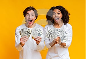 Overjoyed interracial couple holding lot of cash and exclaiming with joy