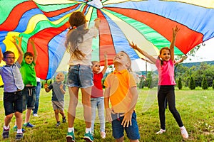 Overjoyed kids bouncing under rainbow canopy textile