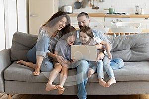 Overjoyed kids watching funny video on computer with parents.