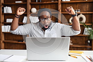 Overjoyed latin black businessman got overwhelming news on laptop