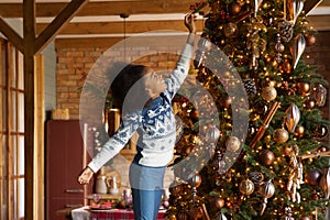 Overjoyed little African American girl decorating Christmas tree at home