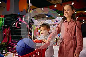 Overjoyed little sister and brother doing shopping in toys shop photo