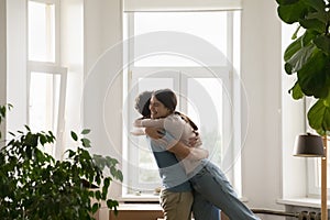 Overjoyed loving young spouses cuddling celebrating relocation day